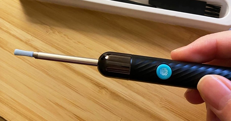 person holding an ear wax removal tool