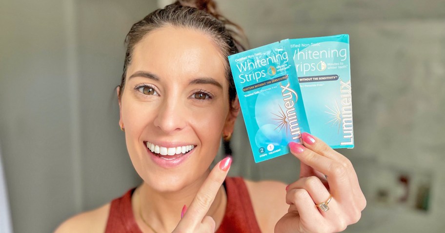 woman holding up and pointing to a set of Lumineux Teeth Whitening Strips