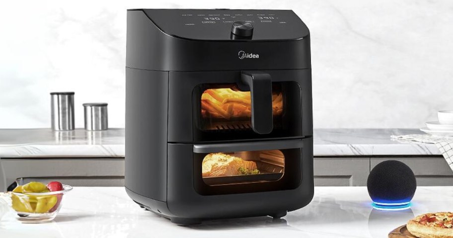 large black 2 basket air fryer oven on a kitchen counter with food cooking in it, Alexa device to the side