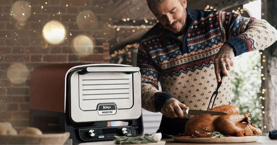 man about to carve a turkey cooked on the ninja woodfire outdoor pizza oven