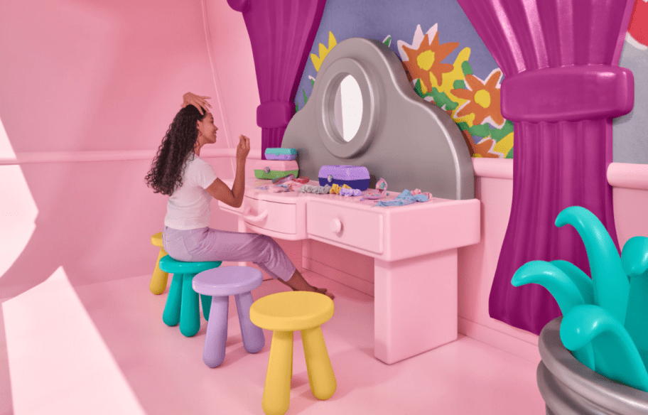 woman sitting at a vanity table in the Polly pocket airbnb