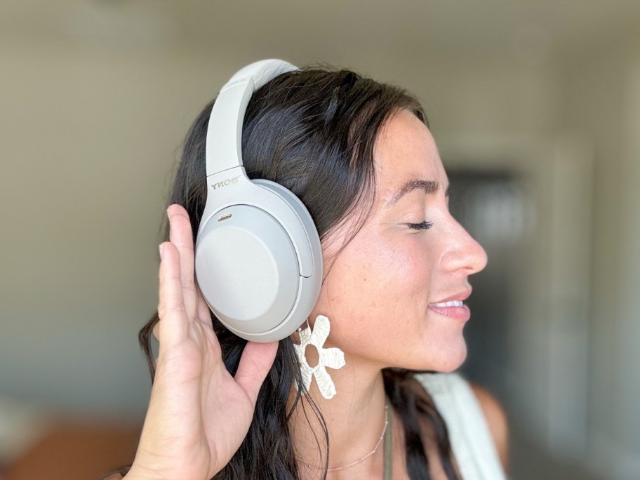 woman wearing silver Sony headphones with her head turned showing them to the camera