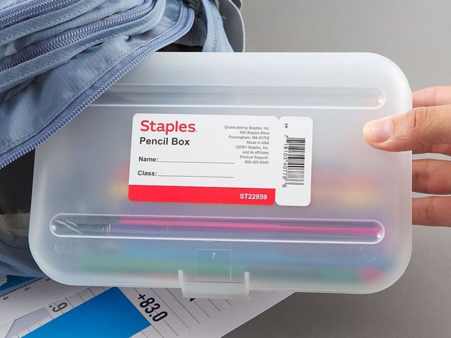 Hand holding a staples clear plastic pencil box