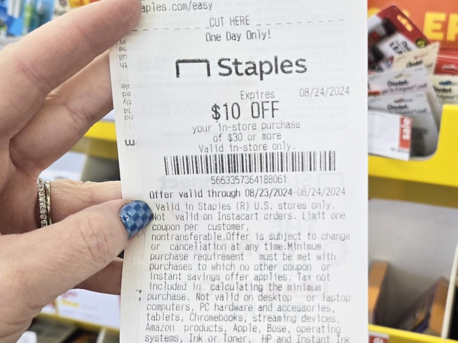 hand holding up a coupon for $10 off a $30 staples purchase from recycling school supplies