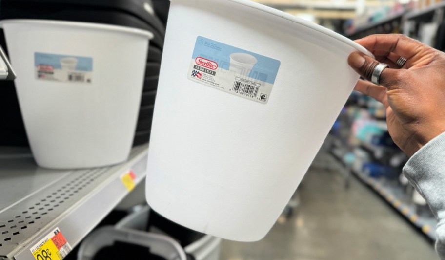 Person taking white trashcan off of shelf inside Walmart store