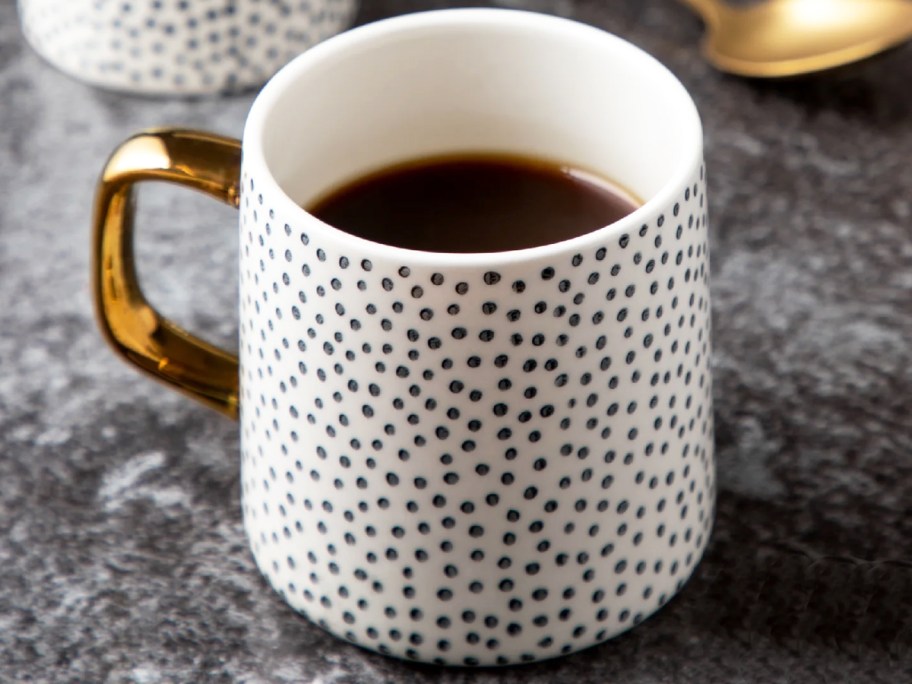 a black and white dotted coffee mug with a gold handle