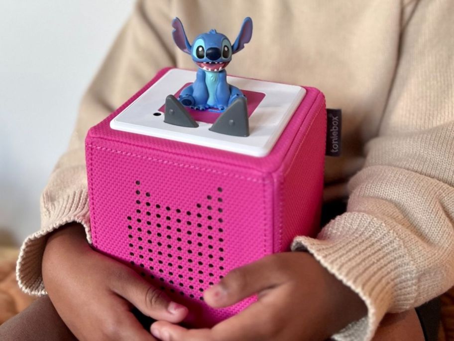 Girl holding a pink Toniebox with a Stitch Tonie on it