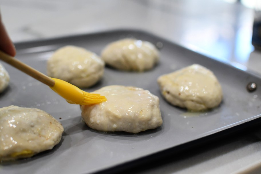 adding butter to the tops of biscuits 