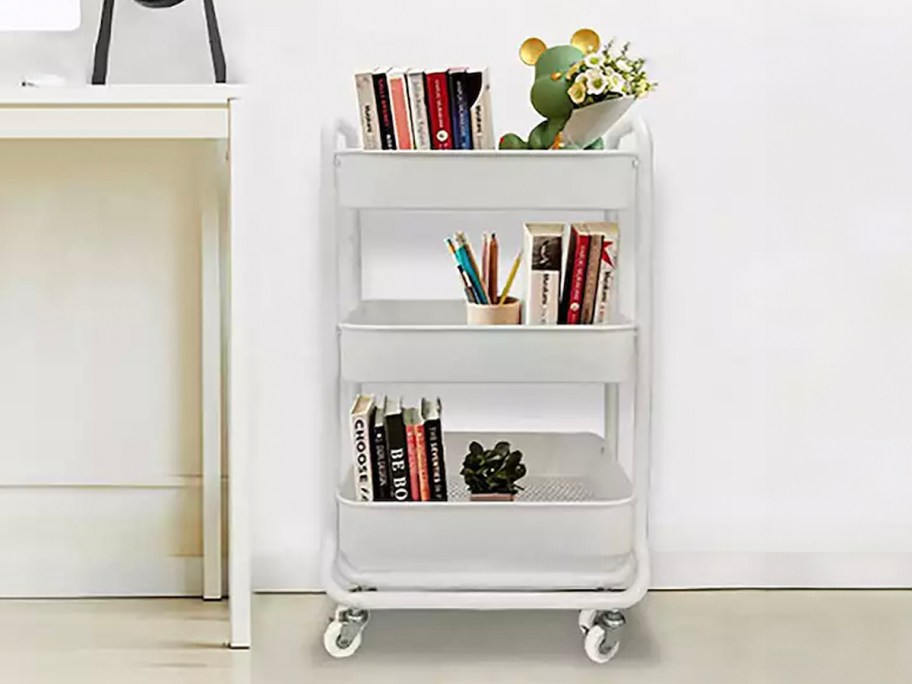 the big one white rolling 3 shelf cart with books and flowers on it