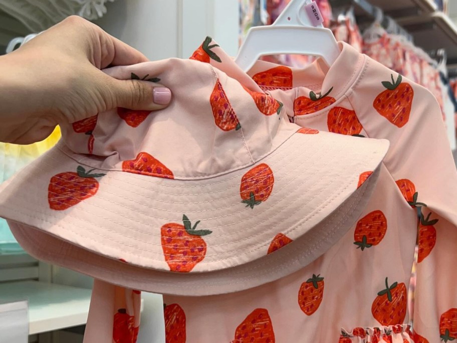 hand holding strawberry baby hat