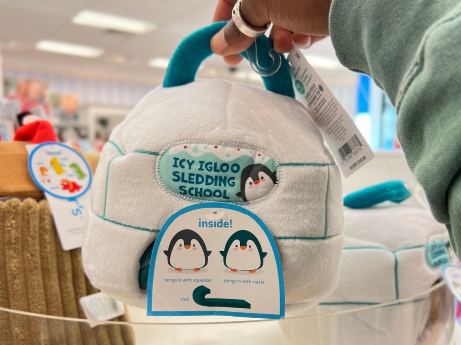 hand holding igloo penguin plush toy