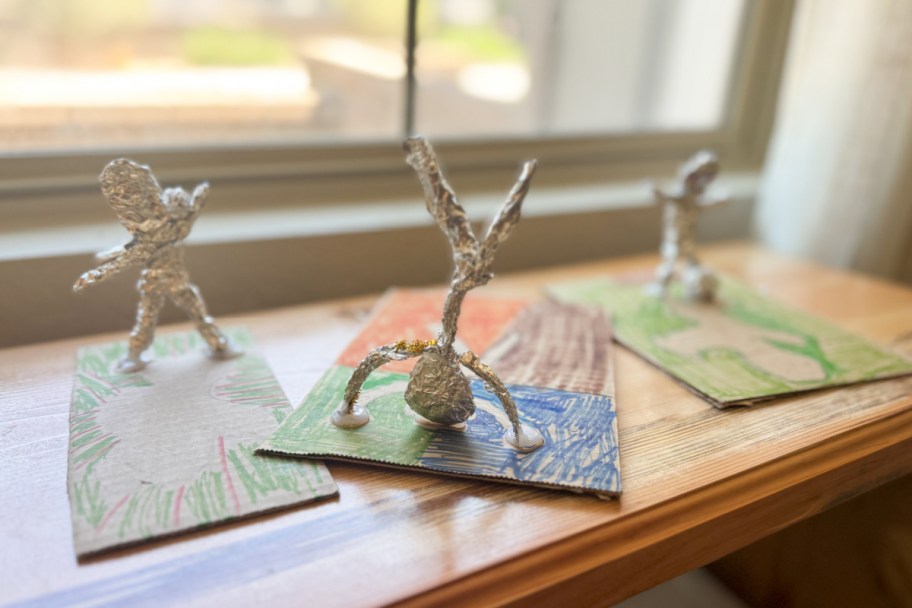 foil statue people on pieces of cardboard