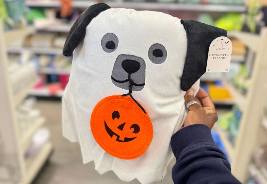a womans hand holding a a ghost dog decorative pillow