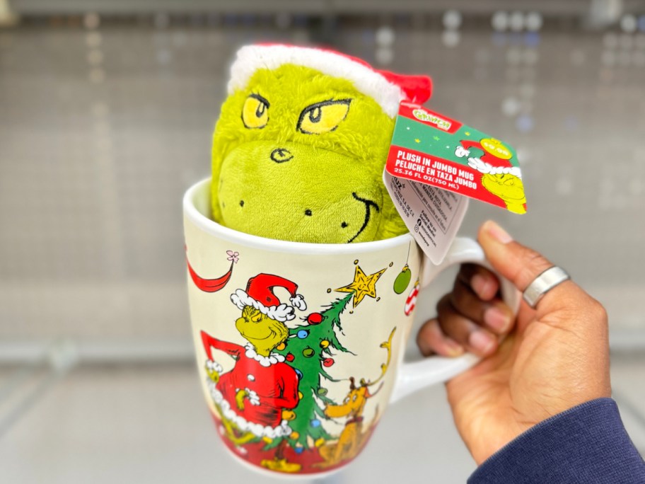 grinch plush inside of mug in womans hand