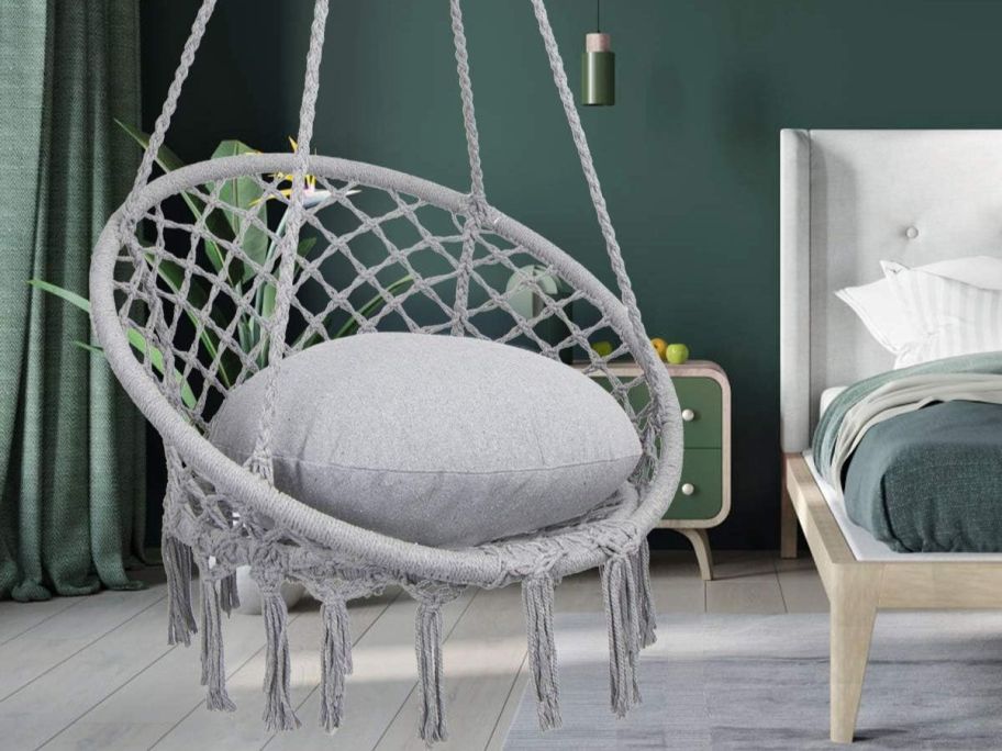 hanging chair with throw pillow on it in front of a bed