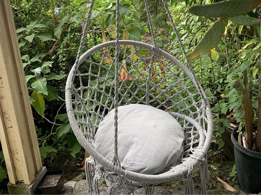 grey hanging chair seated outside in trees