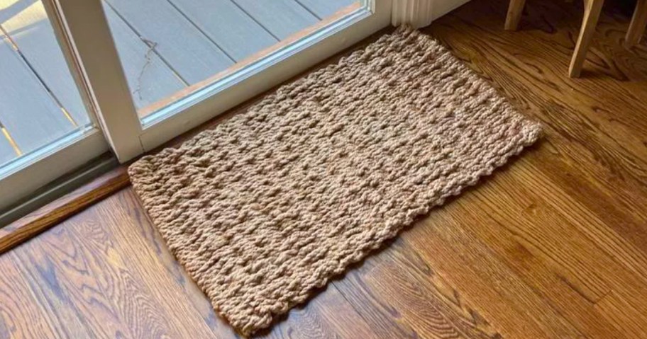 tan jute weave woven doormat in front of a sliding glass patio door on a hardwood floor