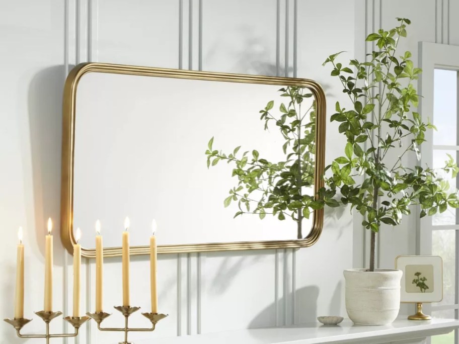 large rectangular brass framed wall mirror above a console table