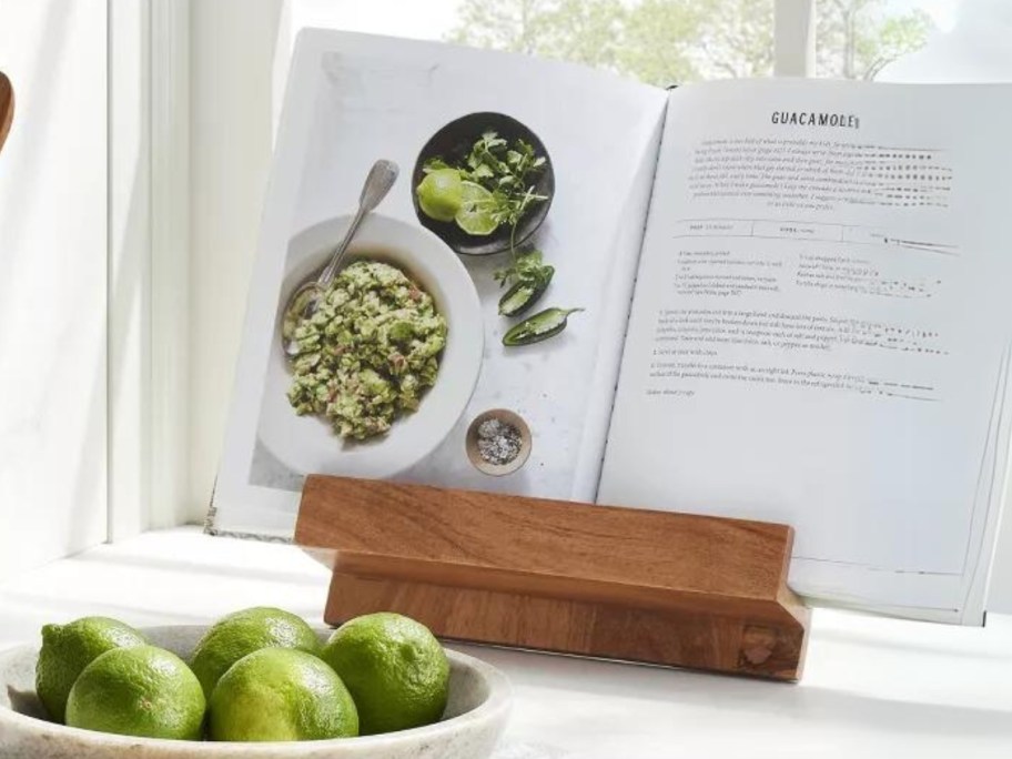 cookbook on a wooden cookbook holder, bowl of limes in front of it