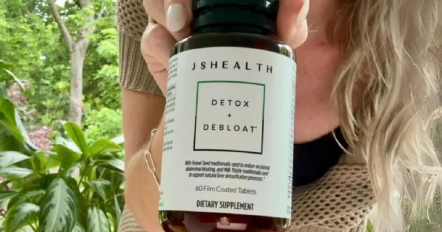 woman holding a bottle of JSHealth Detox and Debloat Supplements up to the camera