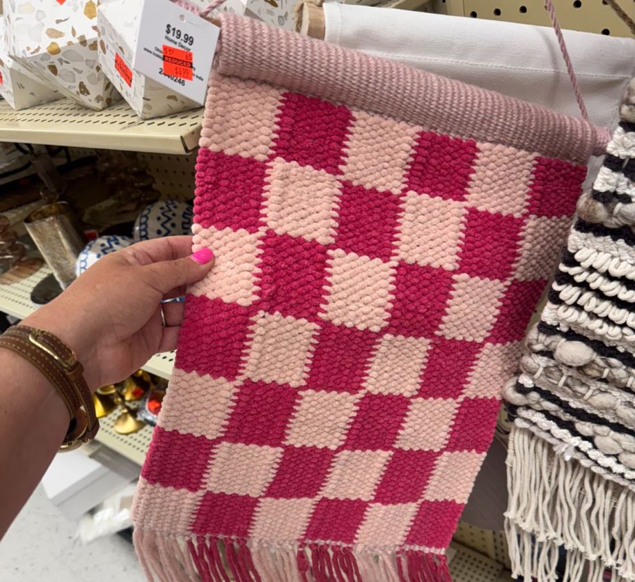 a womans hand holding a piece of woven wall decor