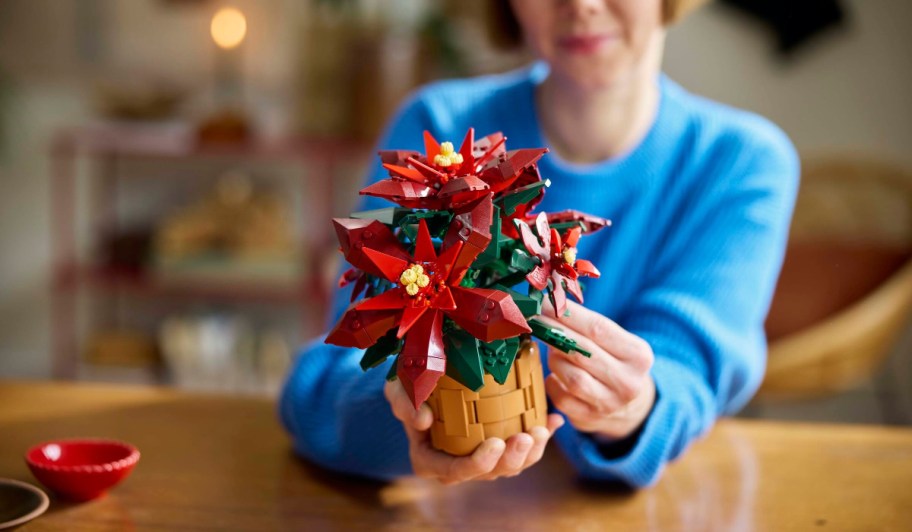 person holding an assembled lego icons poinsetta set