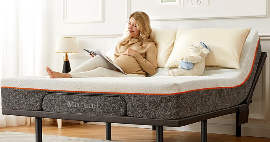 woman laying on adjustable bedframe reading a book 