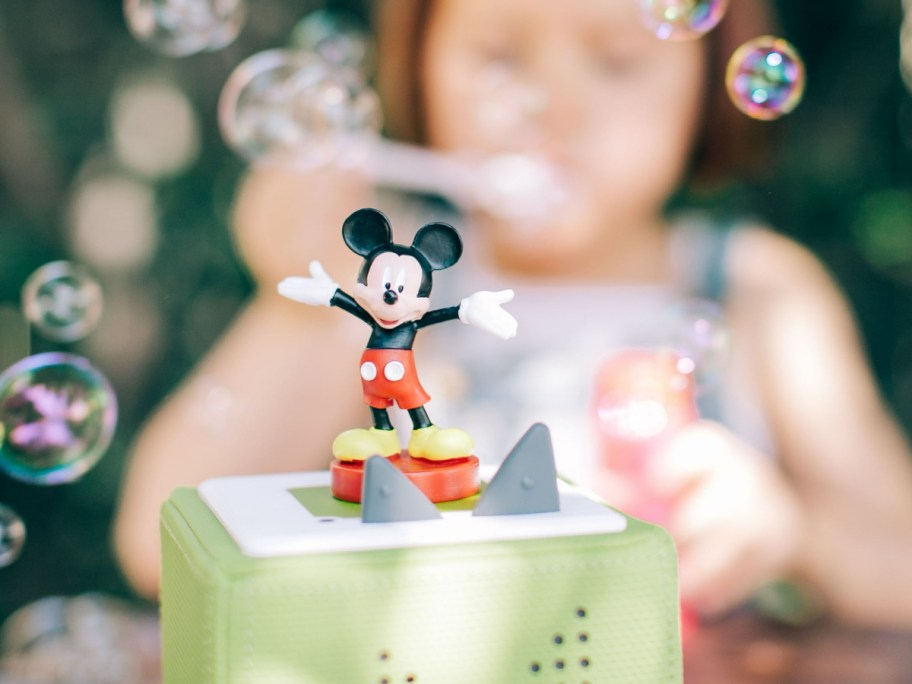 girl blowing bubble behind a mickey mouse tonies