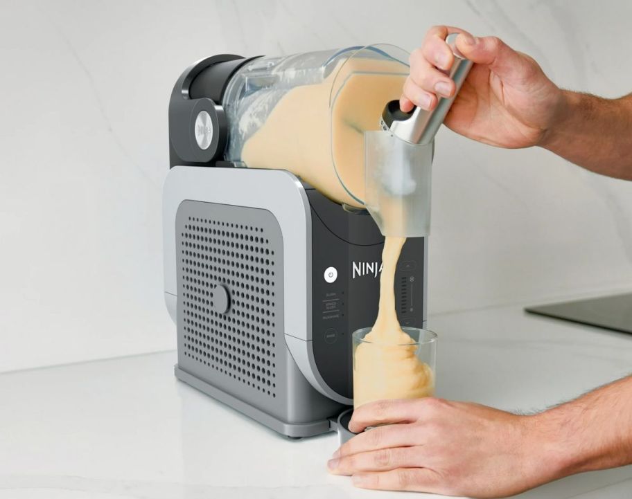 a person's hand shown dispensing a frozen drink from a ninja slushi machine