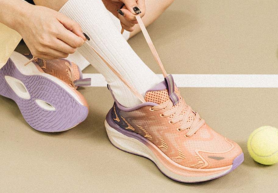 person tying pink and purple shoes 