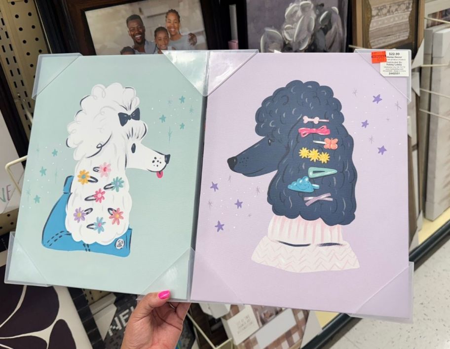 a womans hand holding a pair of framed wall decor