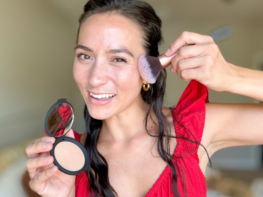 woman swiping highlighter across cheek