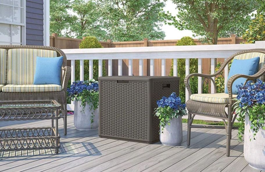 a gray deck box on a deck between two patio chairs