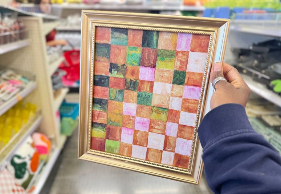 a womans hand holding a framed print