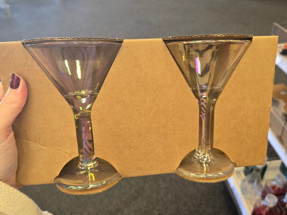 hand holding a set of 2 glass and gold Martini Glasses in a brown packaging