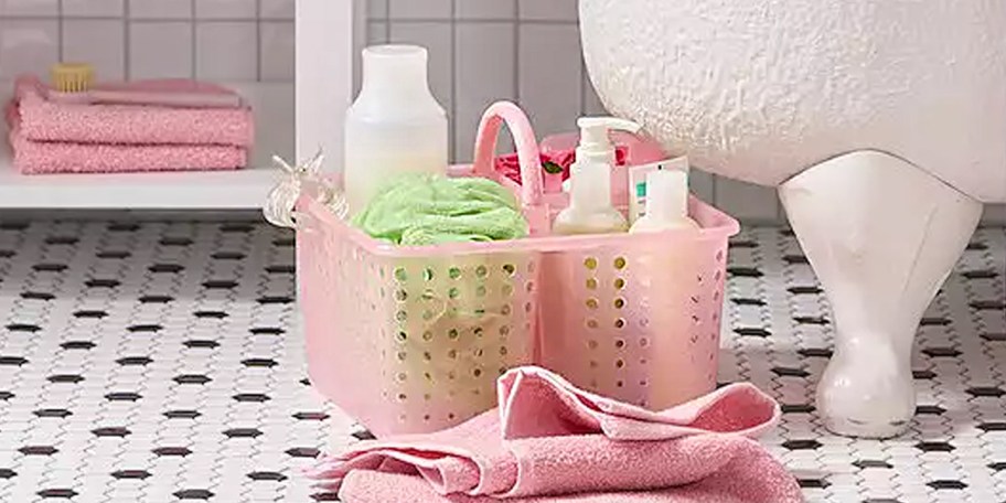 pink shower caddy with products inside on bathroom floor 