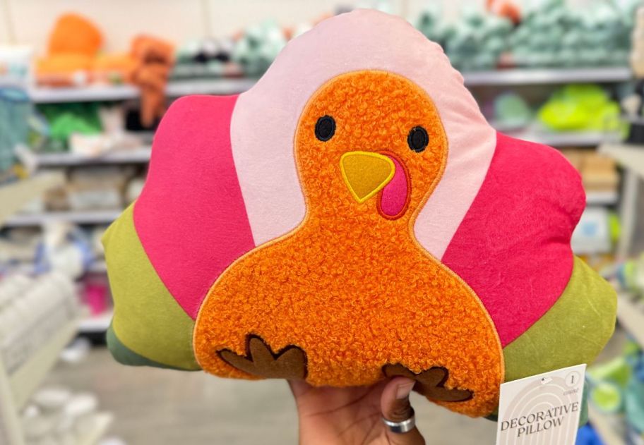 a womans hand holding a turkey shaped pillow