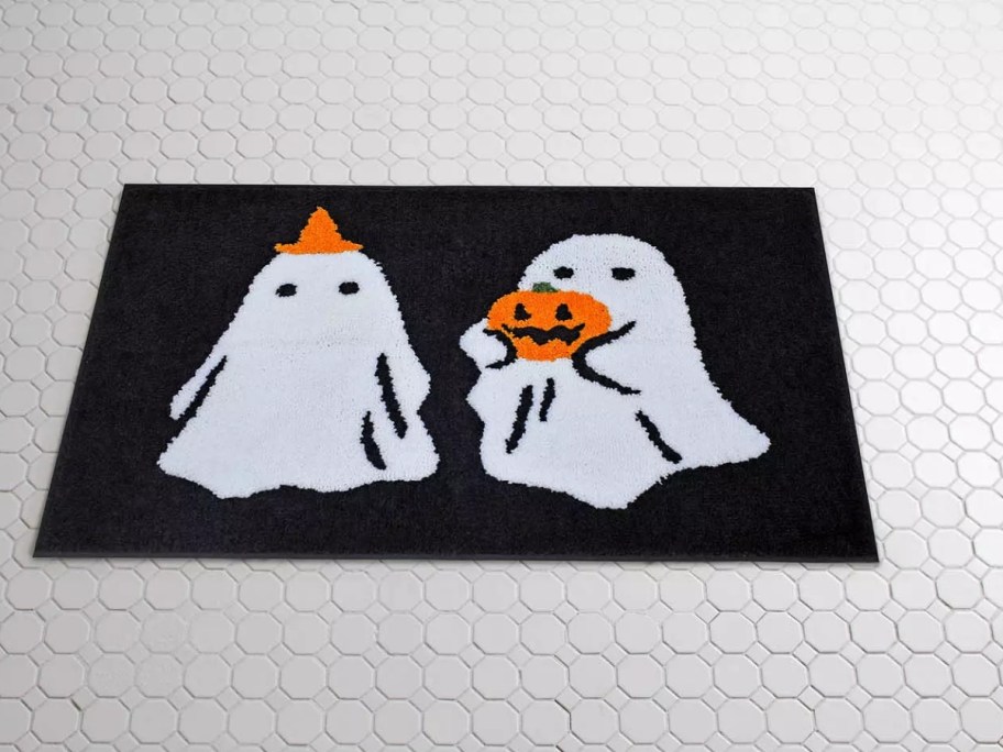 a black bathroom rug with ghosts and pumpkins on it 