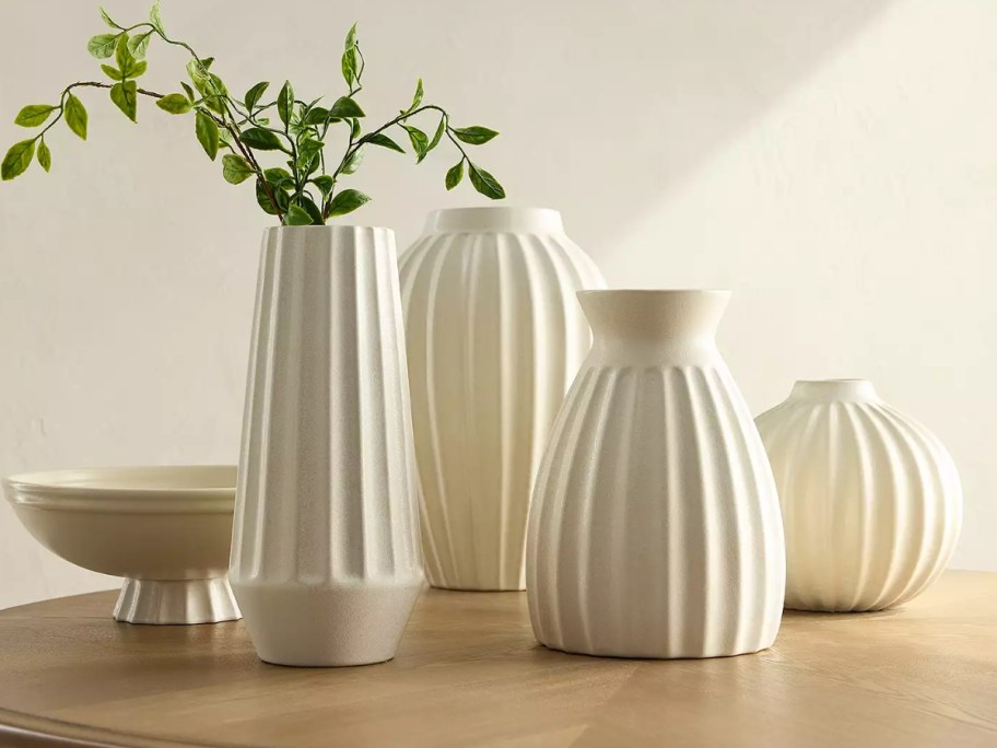 various cream colored ribbed vases and bowls on a table