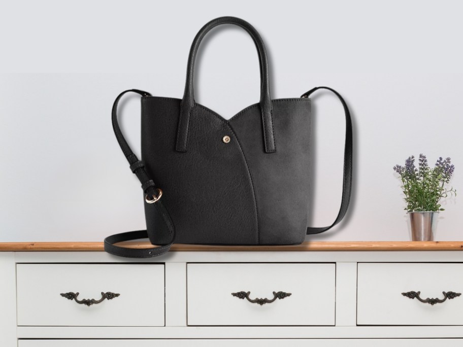 a large black tulip shaped handbag with shoulder strap on a console table