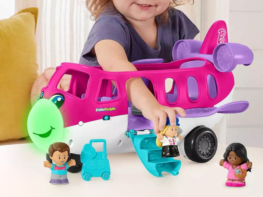 little girl playing with a Barbie Little Dream Airplane & Figures by Fisher-Price Little People set