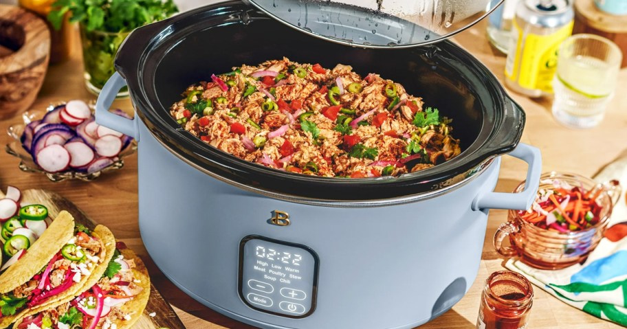 blue slow cooker with shredded chicken inside