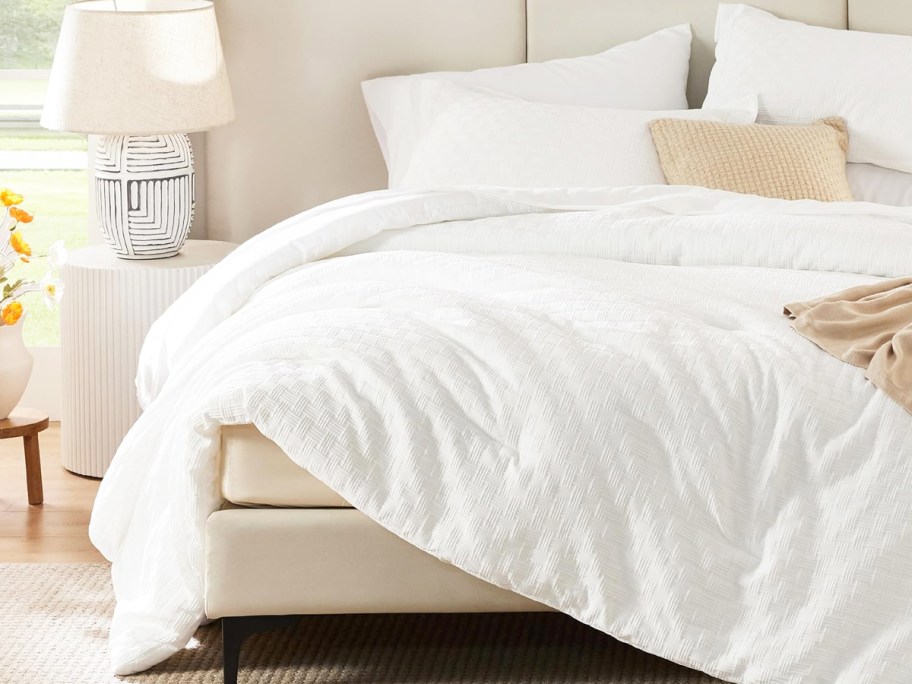 white comforter with matching pillow shams and white sheets on a bed