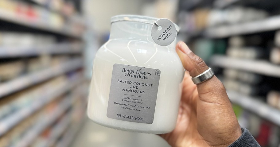 hand holding up a white jar candle in store