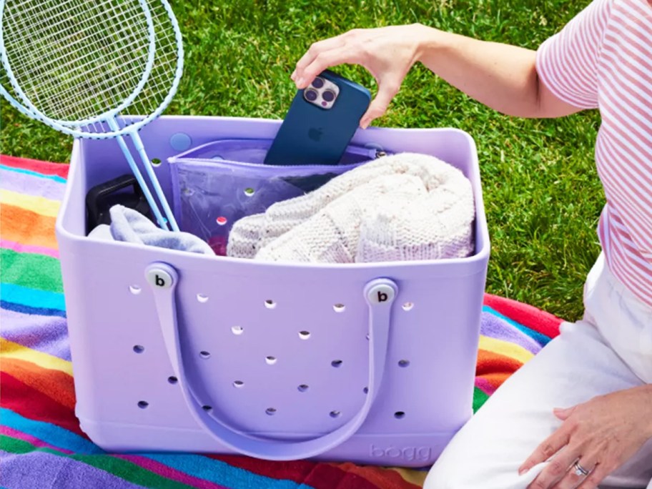 woman grabbing phone out of purple bogg bag