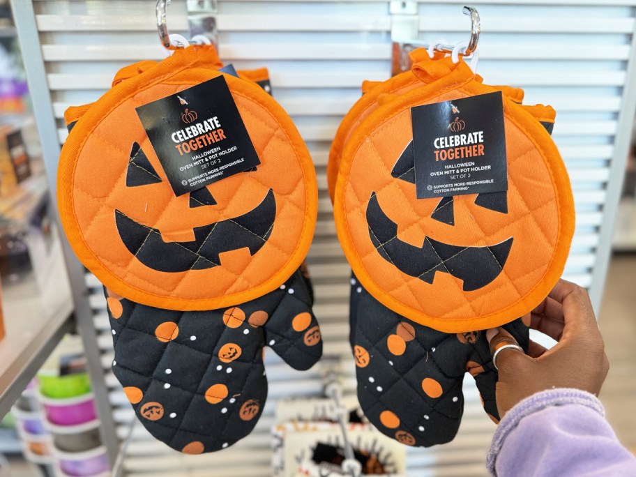 hand touching pumpkin pot holder and oven mitt set