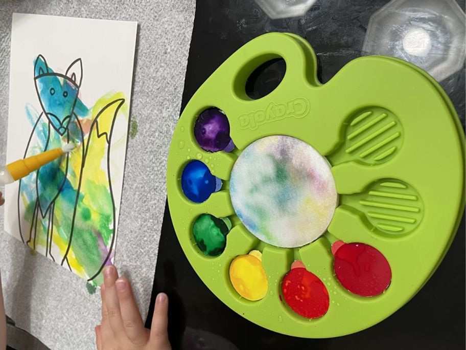 Someone painting a fox with a Craolya palette of washable colors 