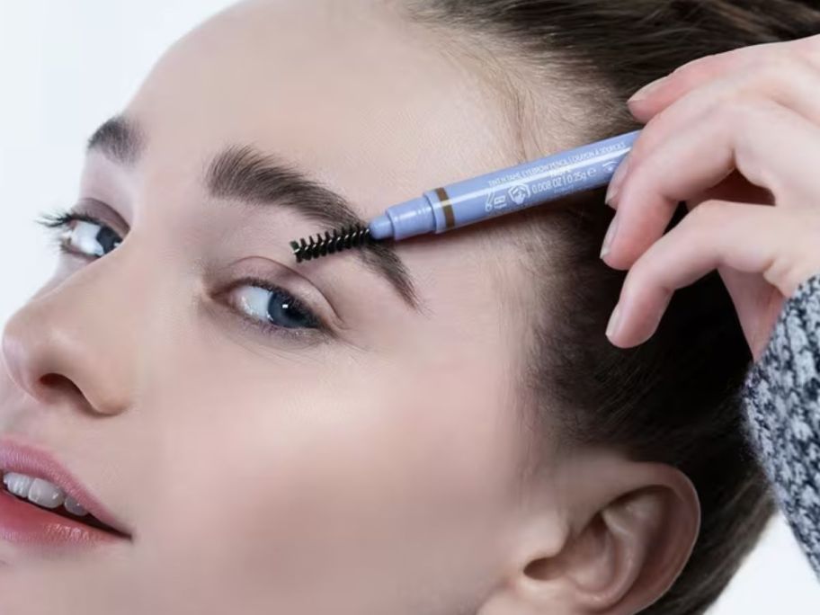 woman using a Florence by Mills Tint N Tame Eyebrow Penci on her brow