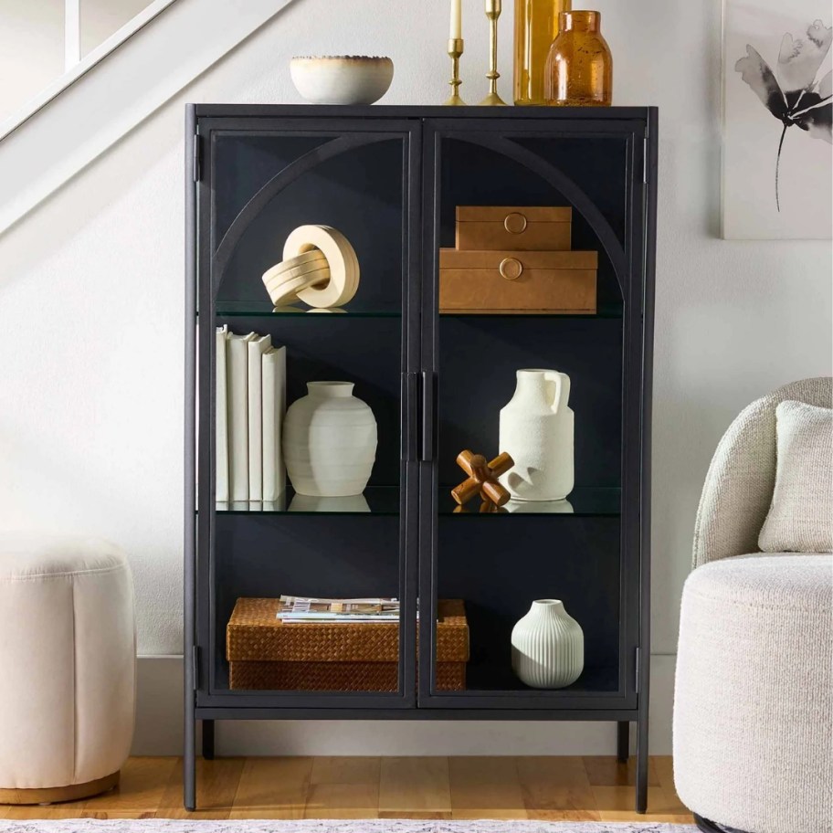 a black accent cabinet with glass doors in a living room