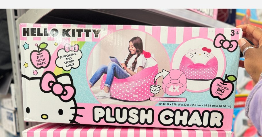 hand reaching for a pink and white box with a kid's Hello Kitty plush bean bag chair in it